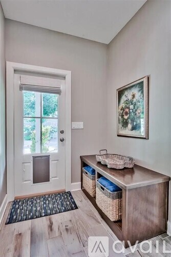 A room with a white door, a wooden cabinet, and a framed picture on the wall.