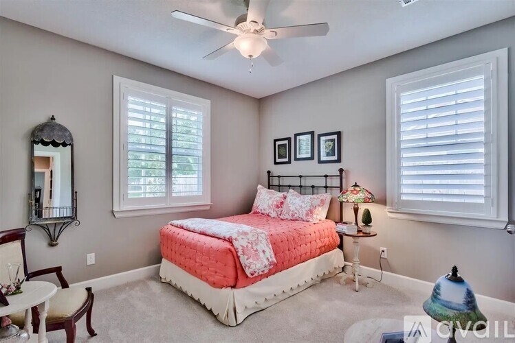 A bedroom with a bed, chair, and pictures on the wall.