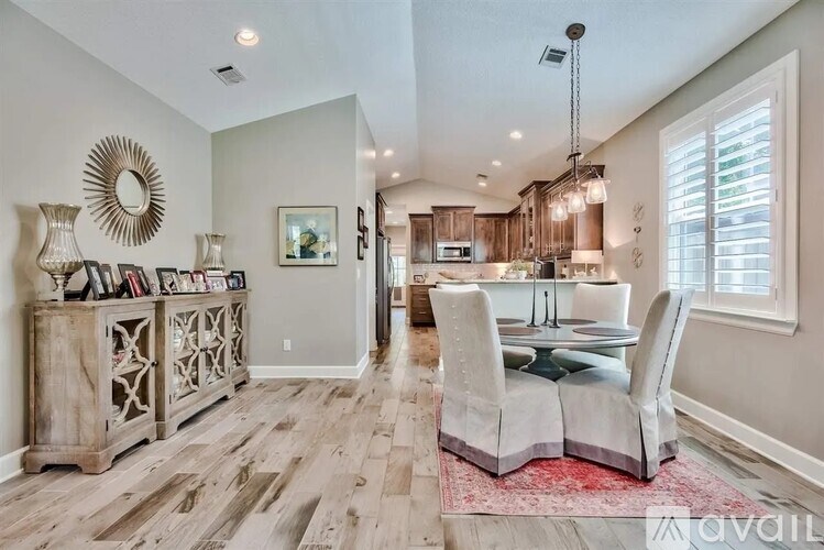 A dining room with a wooden floor and a large mirror on the wall.