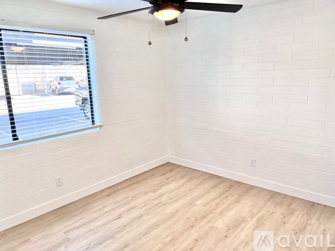A room with a ceiling fan and a window with blinds.