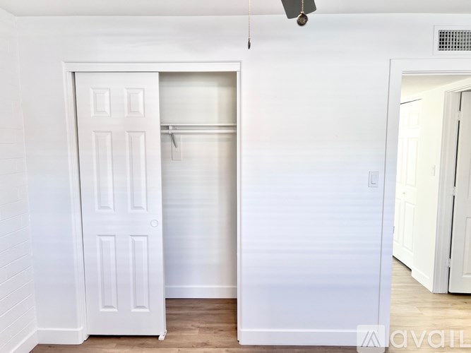 A white door is open to a room with a wooden floor.