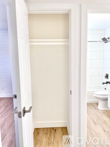 A white door is open to a bathroom with a toilet and a shower.
