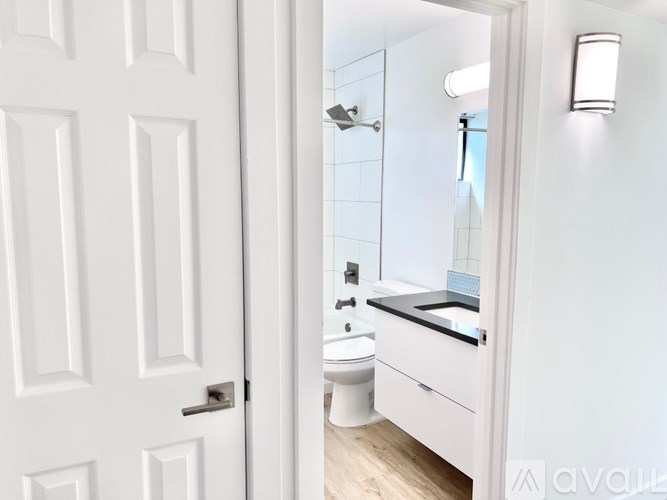 A white door opens to a bathroom with a toilet and sink.