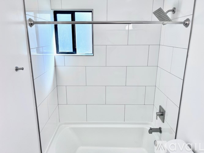A white tiled bathroom with a window.