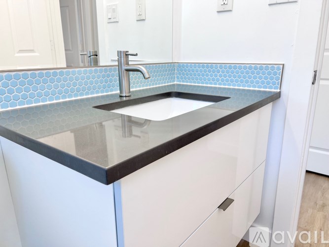 A modern bathroom with a black countertop and a silver faucet.