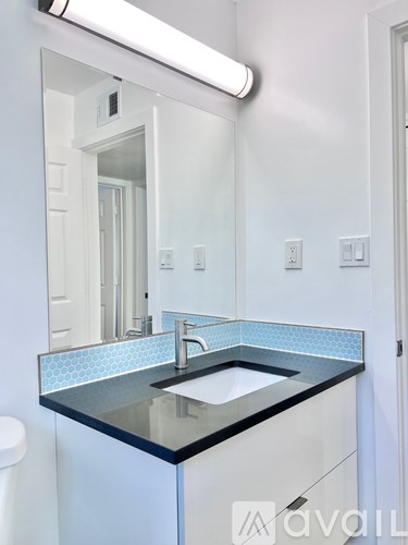 A bathroom with a black countertop and a white toilet.