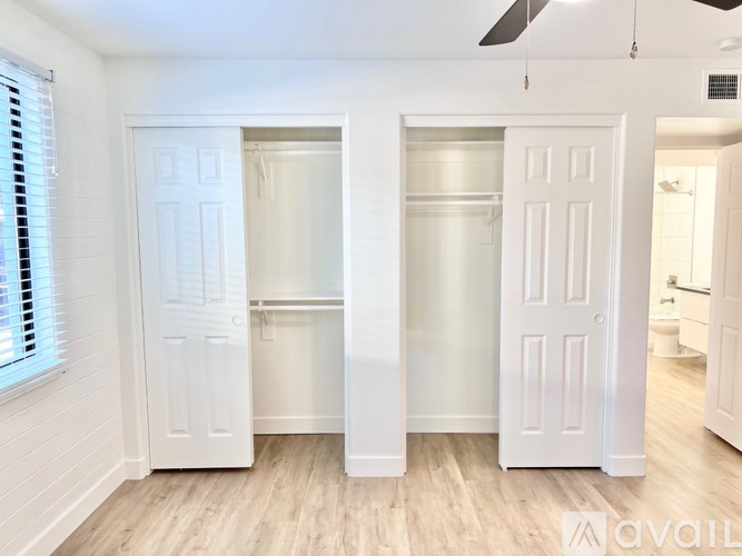 A room with two white doors and a window with blinds.