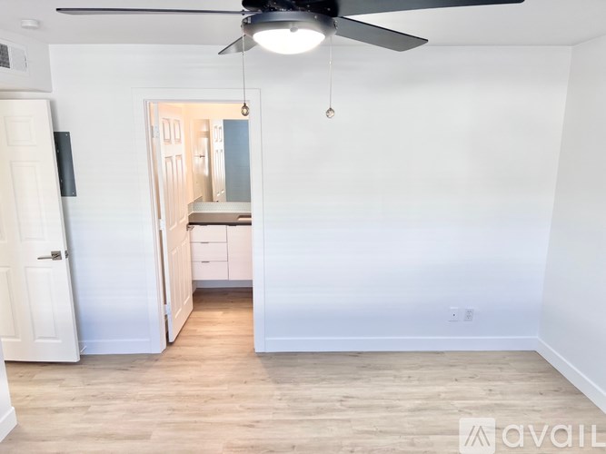A room with a ceiling fan and a door leading to another room.