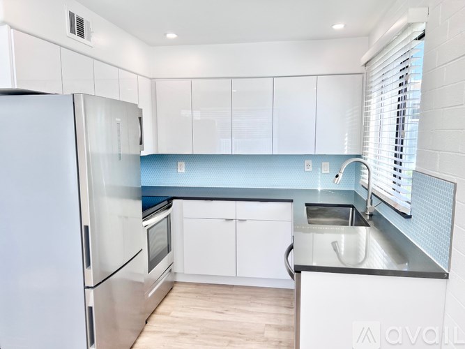 A kitchen with white cabinets and a stainless steel refrigerator.