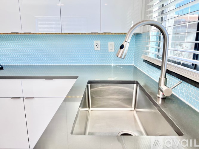 A modern kitchen with a stainless steel sink and white cabinets.