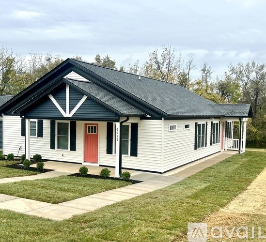 A white house with a red door and a black roof.