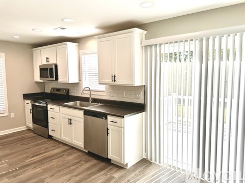 A kitchen with white cabinets and black countertops.