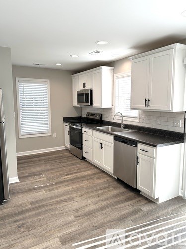 A kitchen with white cabinets and a black countertop.