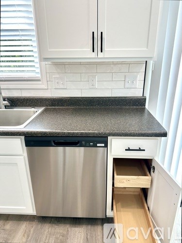 A kitchen with white cabinets and a stainless steel dishwasher.
