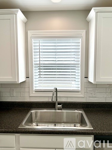 A kitchen with a sink and a window with blinds.