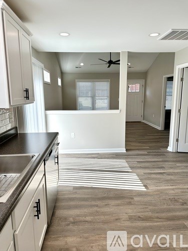 A kitchen with white cabinets and a striped rug on the floor.