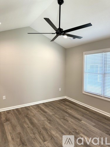A room with a ceiling fan and wooden flooring.
