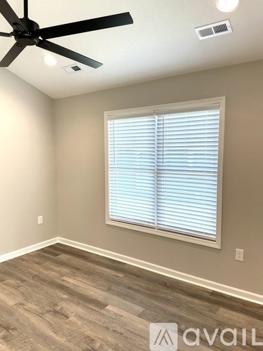 A room with a ceiling fan and a window with blinds.