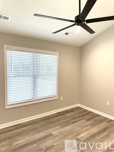 A room with a ceiling fan and a window with blinds.