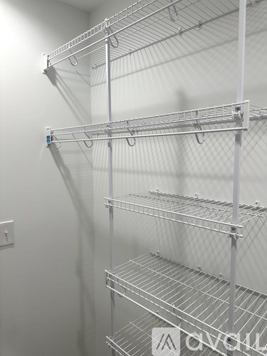 A white wall with a metal shelf on it.