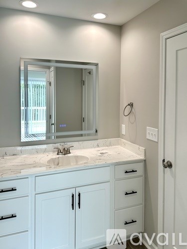 A bathroom with a sink, mirror, and cabinets.