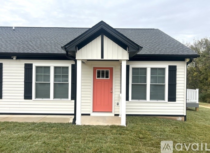 A white house with a red door and black shutters.