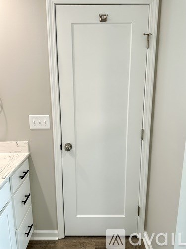 A white door with a silver handle and a silver lock.