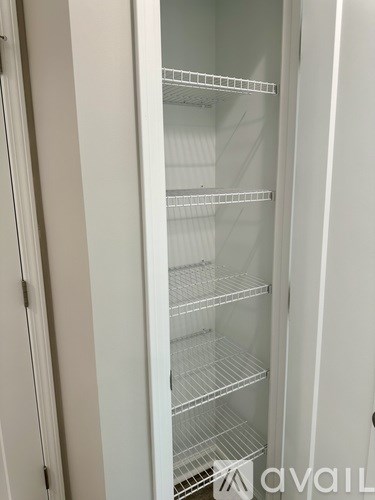 Empty white refrigerator with four shelves.