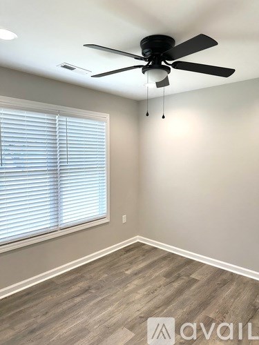 A room with a ceiling fan and a window with blinds.