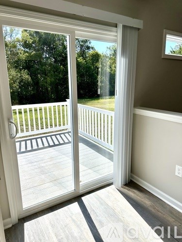 A sliding glass door opens to a deck with a white railing.