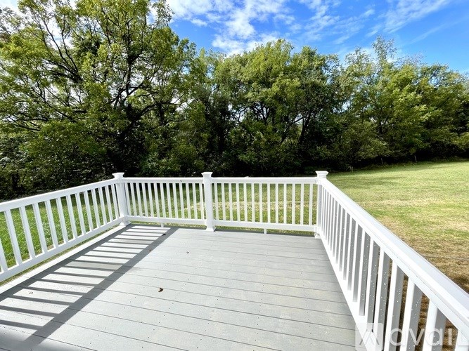 A white deck with a railing overlooks a grassy area.
