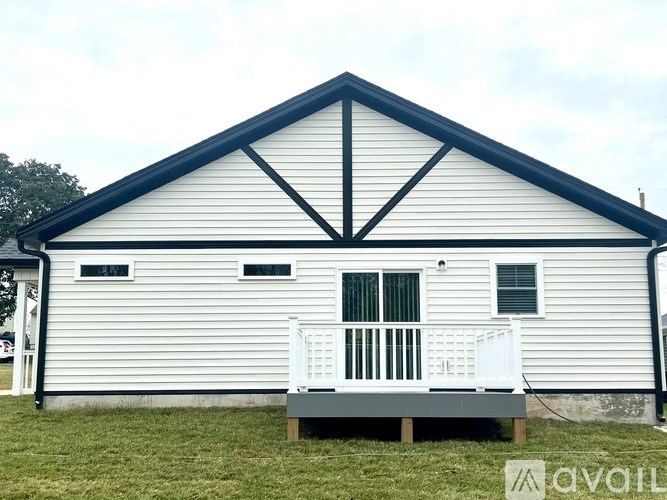 A white house with a black roof and a porch.