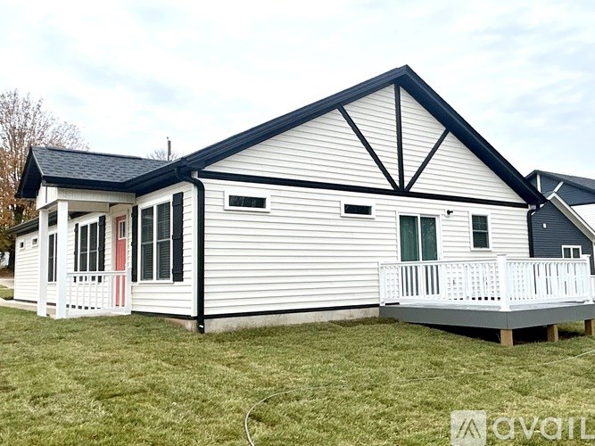 A white house with a black roof and a porch.