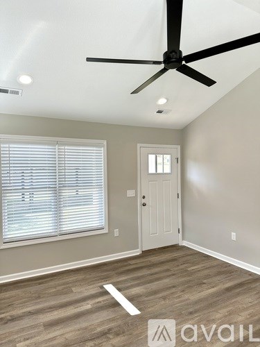 A room with a ceiling fan and a door.