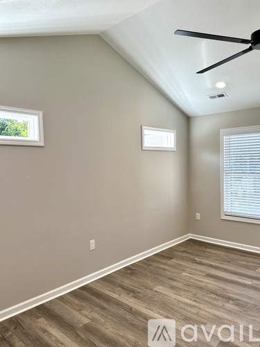 A room with a ceiling fan and a window with blinds.