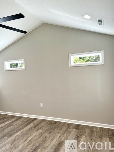 A room with a ceiling fan and two windows.