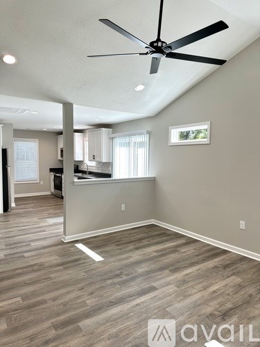 A room with a ceiling fan and wooden flooring.