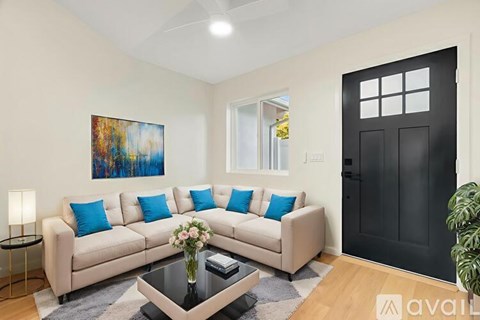 A living room with a beige couch, a coffee table, and a painting on the wall.