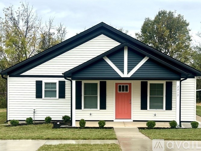 A white house with a red door and a black roof.