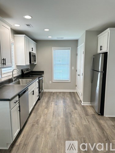 A kitchen with white cabinets and a black countertop.