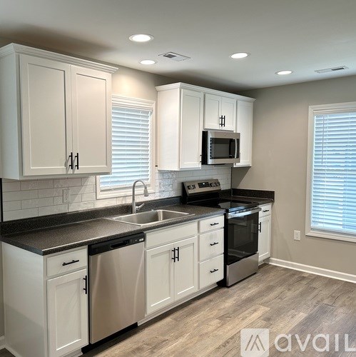 A kitchen with white cabinets and black countertops.