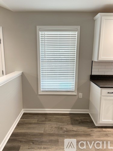 A kitchen with a window covered in white blinds.