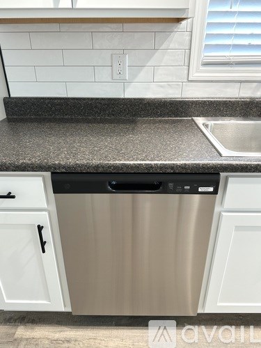 A kitchen with a stainless steel dishwasher and white cabinets.