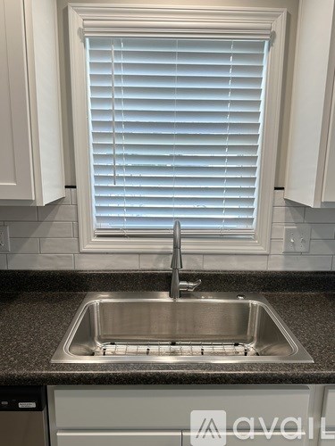 A kitchen with a sink and a window with blinds.