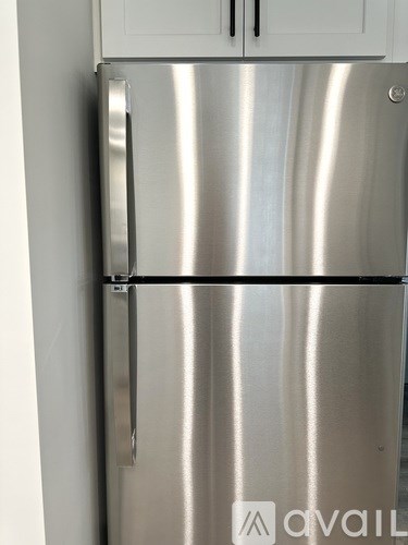 A stainless steel fridge with a white cabinet on top.