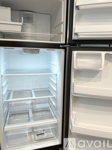 A white refrigerator with the door open showing the empty shelves.
