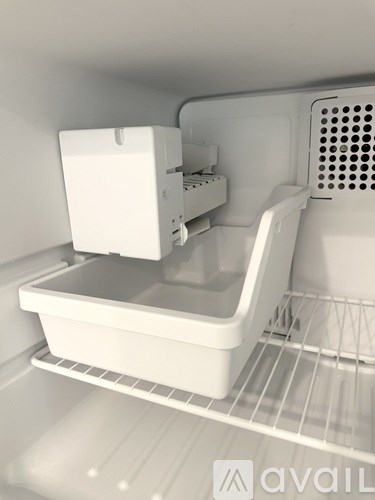 A white container is placed on a shelf inside an empty refrigerator.
