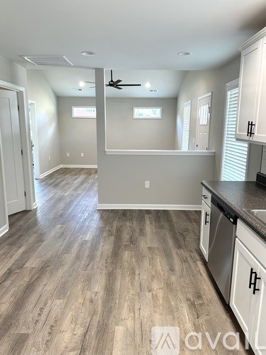 A kitchen with wooden floors and white cabinets.