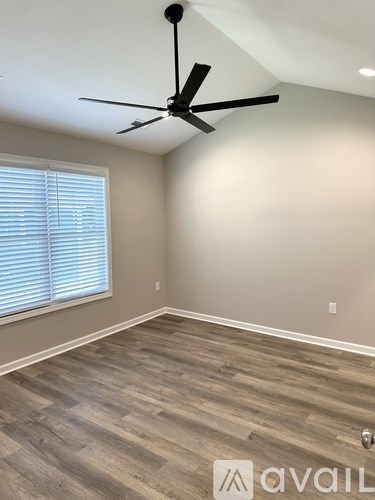 A room with a ceiling fan and wooden flooring.