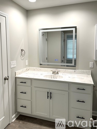 A bathroom with a sink, mirror, and cabinets.